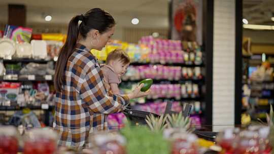 一个黑发女人穿着格子衬衫，怀里抱着她的小