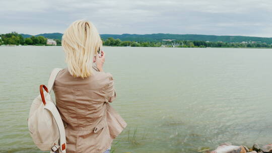 女人用手机拍摄湖泊全景