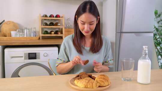 亚洲有魅力的女人在家里的厨房里吃美味的饼