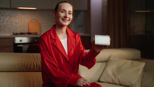 穿着红色睡衣的微笑女人在舒适的客厅里展示视频素材模板下载