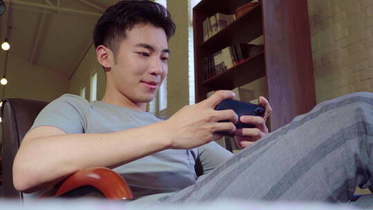 年轻男人用手机玩游戏视频素材模板下载
