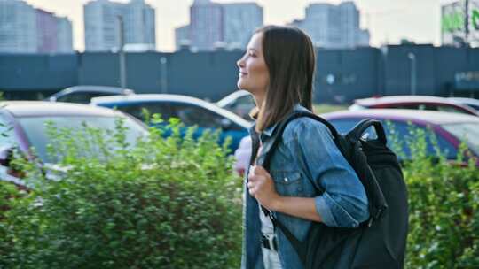 快乐的年轻女子背着背包走在现代城市的街道