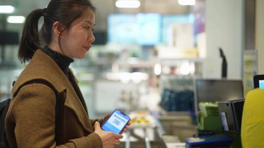 女性在超市使用扫码支付手机支付无线科技
