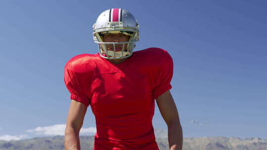 戴着头盔和橄榄球站着的美国足球运动员视频素材模板下载