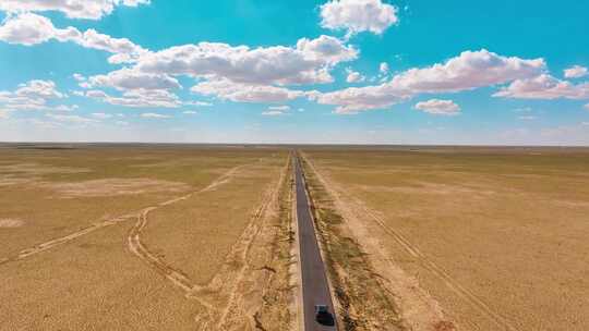 航拍秋季草原上的公路和行驶车辆的壮阔景象