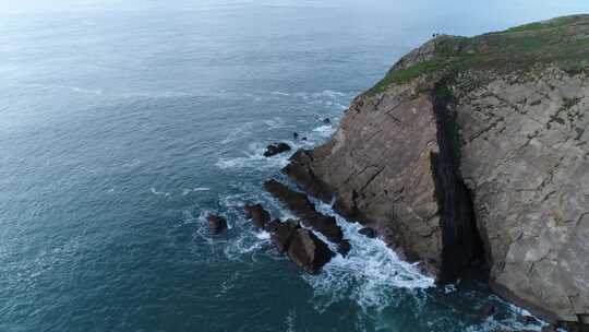 航拍蓝色海岸岩壁，海浪拍打岩石视频素材模板下载