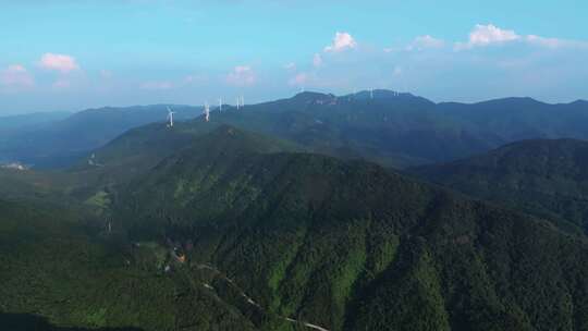 航拍崇山峻岭间山顶的水库与风力发电场风机