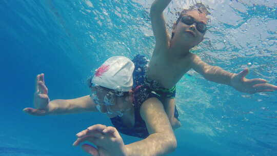小男孩和妈妈一起在水下学习游泳潜水