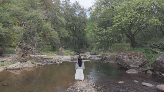 女子于溪边舒展双臂放松