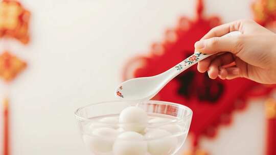 手持勺子舀取碗中元宵