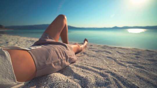 一名女孩躺在沙滩上晒日光浴视频素材模板下载