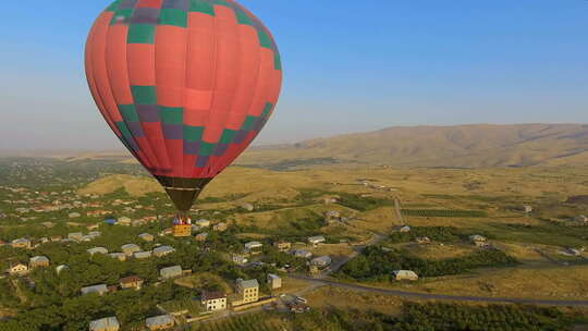 巨大的五彩热气球飞过亚美尼亚村庄，风景