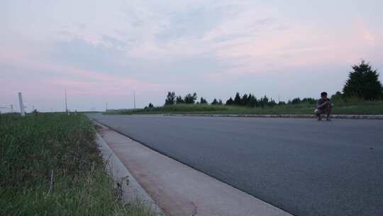 朋友记录一名男性滑板手在空旷道路上滑板技