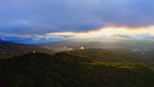 夕阳透过云层染红了山林