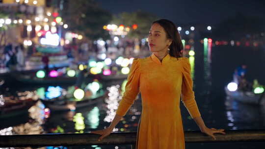 穿着传统服装的年轻越南妇女看着海市夜河倒