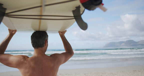 海滩上拿着冲浪板的男人