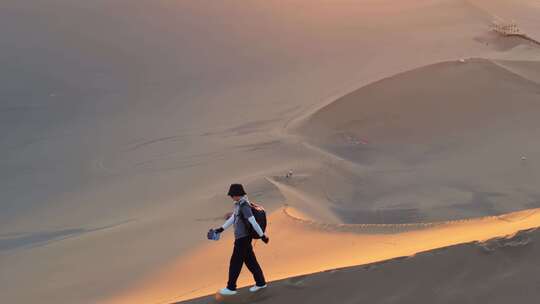 航拍男人行走在新疆库木塔格沙漠中
