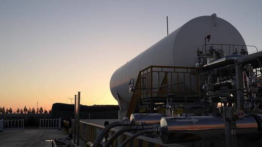 夕阳下高压电线塔附近巨大的储气罐航拍视频素材模板下载