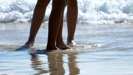男的和女的脚都站在沙滩上