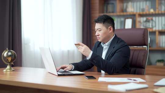 亚洲商人在办公室的笔记本电脑上进行在线支