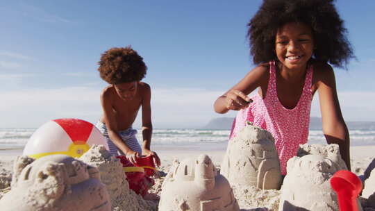 非洲裔美国人兄弟姐妹在海滩上玩沙子