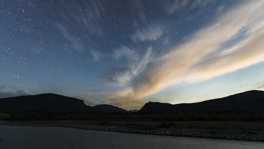 夜晚星星在水面和山脉上移动