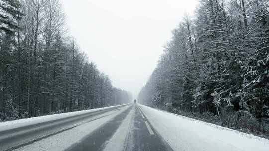 冬季POV在雪暴期间在白天的森林道路上驾驶卡车