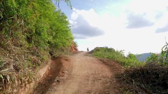 两个人在山区的土路上骑摩托车