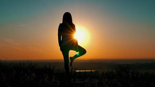 黄昏女人面对太阳做瑜伽