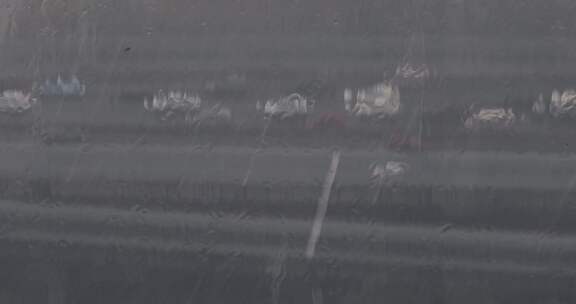 暴雨雨滴打在窗玻璃上窗外车流