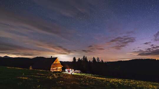 在宁静的夏夜大自然星空中与朋友坐在小屋旁