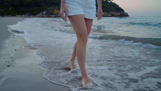 年轻女子走在海滩的水边