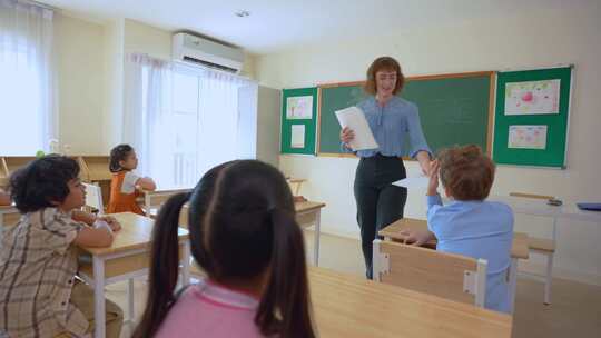 高加索年轻女子教师在学校教室里教学生。A