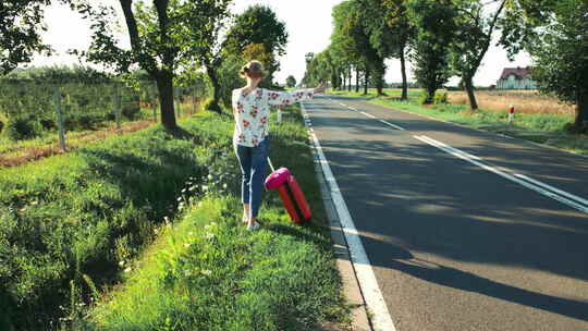 旅行者女孩在阳光明媚的路上搭便车和散步