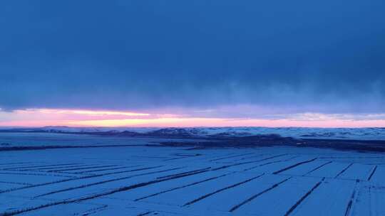 航拍浓郁夕阳下的垦区雪原