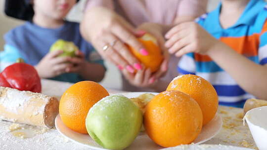 小孩子和妈妈在厨房刷水果。儿童手柄特写