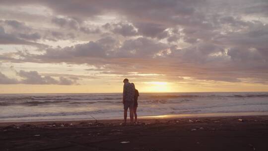 情侣在夕阳时分的海滩散步
