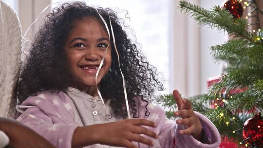 在圣诞树旁玩丝带的孩童视频素材模板下载