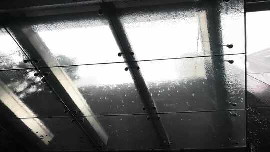 雨水落在现代结构的坚硬玻璃屋顶天花板上。视频素材模板下载