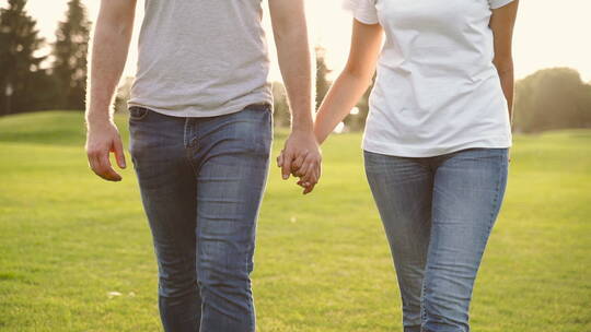 夫妇牵着手在草地上散步