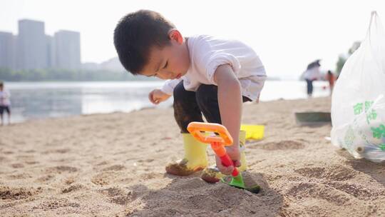 小男孩在河边的沙滩上挖沙子堆城堡