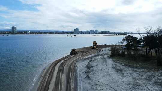 揭示了重型机械在海岸侵蚀项目的搁浅沙滩上工作的无人机视图。爸