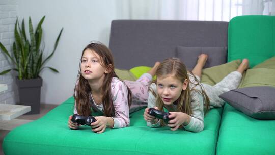小女孩趴在沙发上玩电子游戏视频素材模板下载