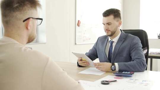 一名男子向他的同事展示平板电脑屏幕