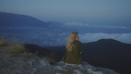 女人坐在山顶背影