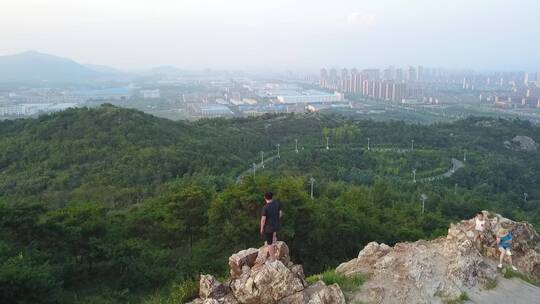 男人站在山顶俯瞰远方的城市