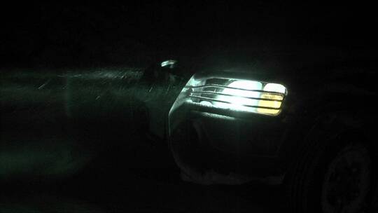 夜晚雪花中汽车前灯的特写镜头
