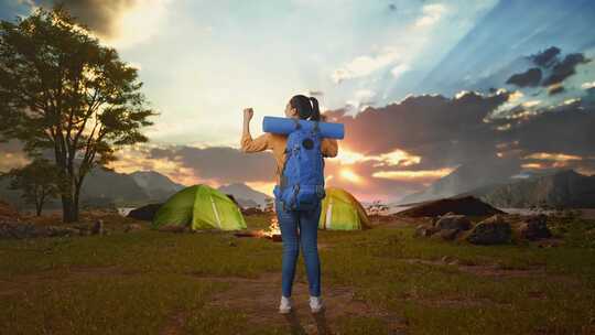 一名女性徒步旅行者在湖边帐篷营地庆祝的全