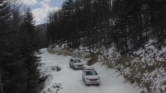 越野车在下雪的山区丛林冰雪路面运输航拍4k