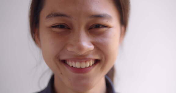 一名十几岁的亚洲女高中生正在开心地微笑。